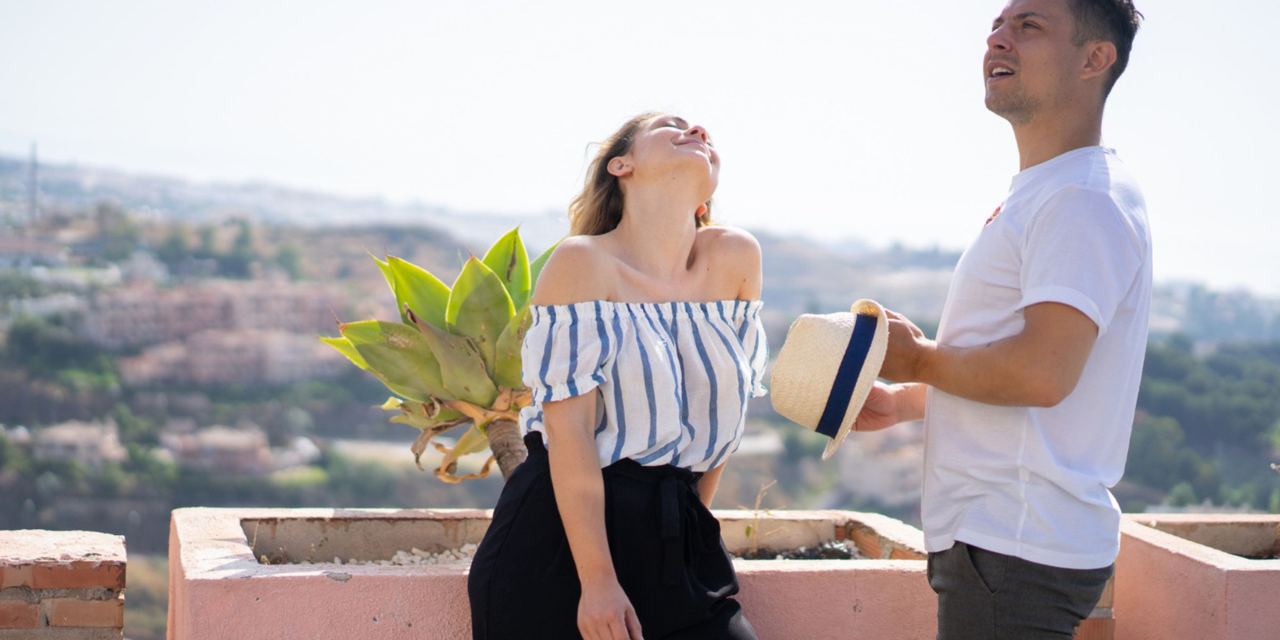 A smiling couple enjoying a sunny overlook together, sharing a carefree moment with scenic views stretching into the distance | Source: Magnific