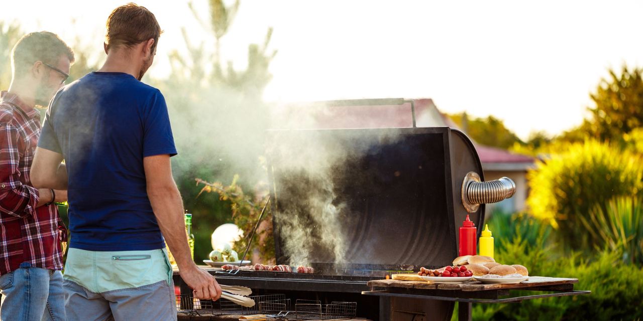 Two young men standing at a barbecue grill | Source: Magnific