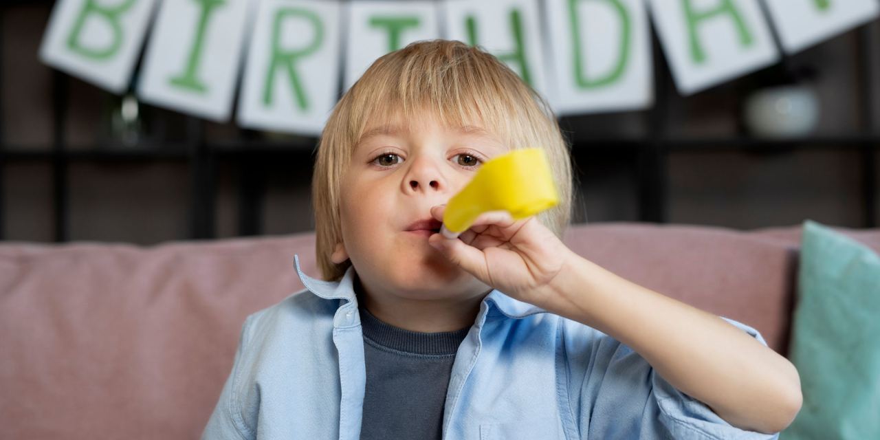 A little boy celebrating his birthday by blowing a whistle | Source: Magnific