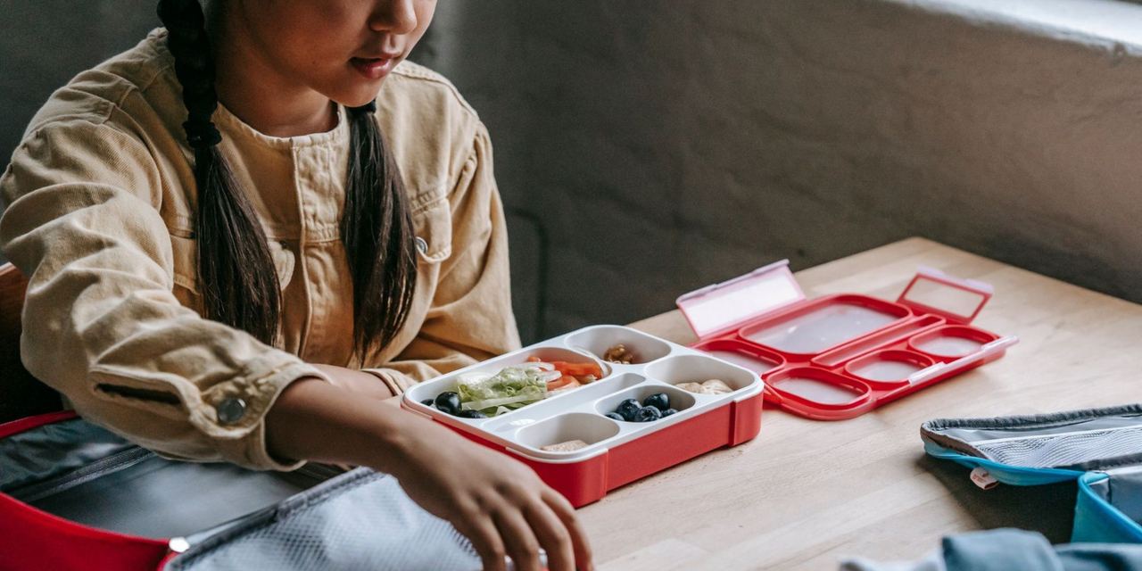 Girl preparing a healthy packed lunch at the table | Source: Pexels