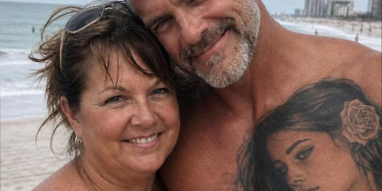 A smiling couple posing for a beach selfie, with the man showing a large portrait tattoo on his chest | Source: AmoMedia
