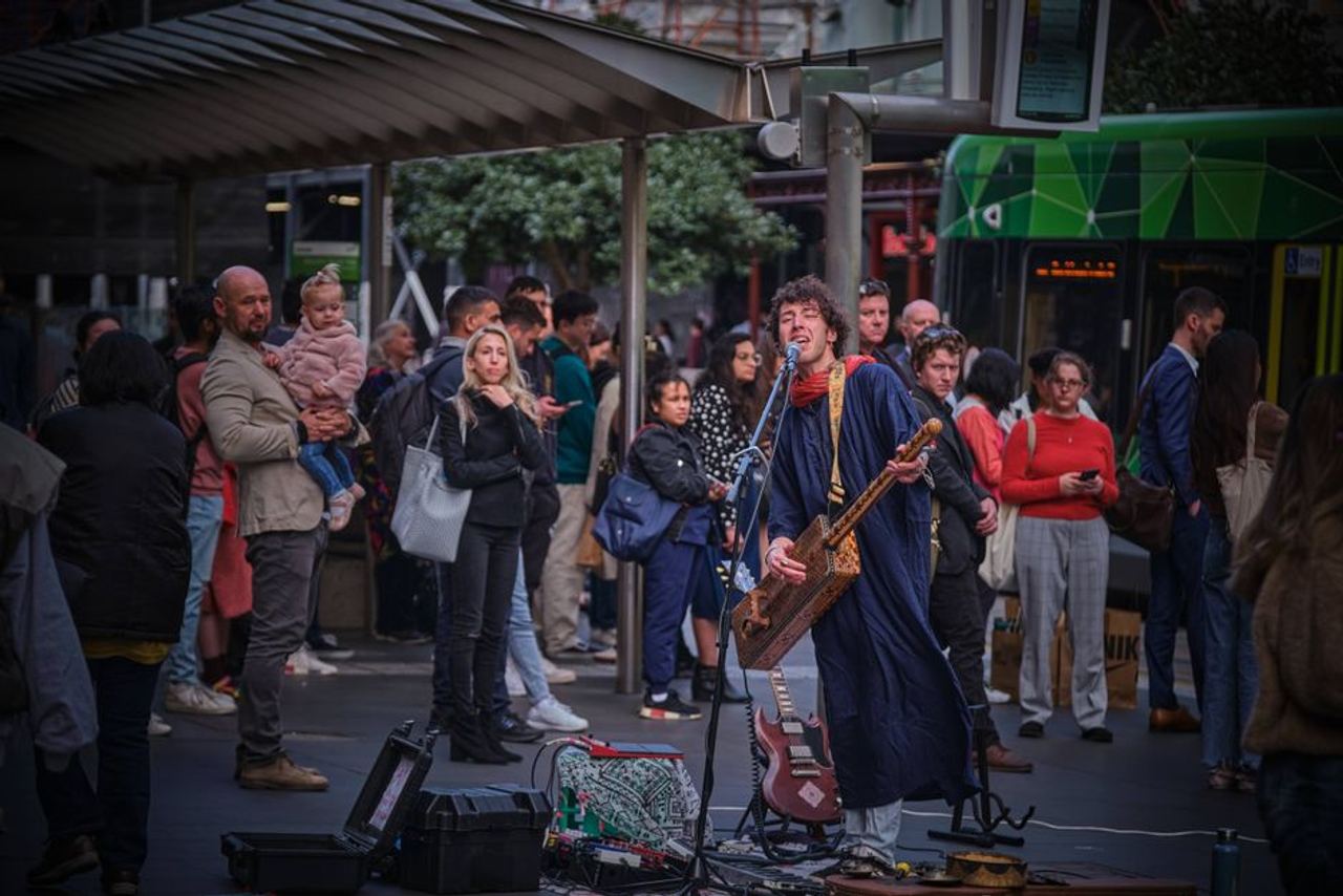 Busker performing outdoors, drawing attention in a busy city environment.