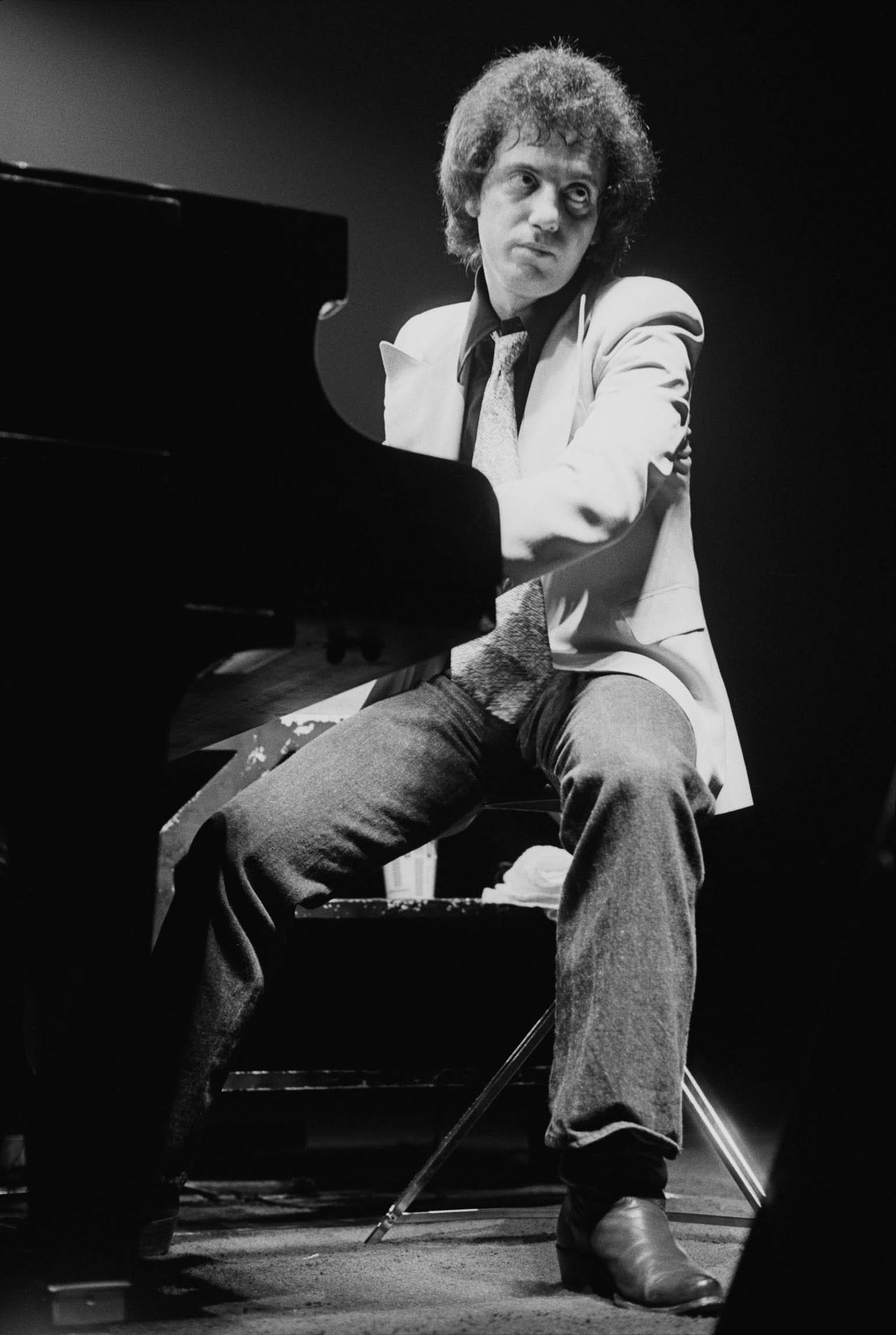 Billy Joel at the piano during his 1970s concert years. Archive photograph reproduced by Esquire; not a photograph of the bar patrons described in the song.