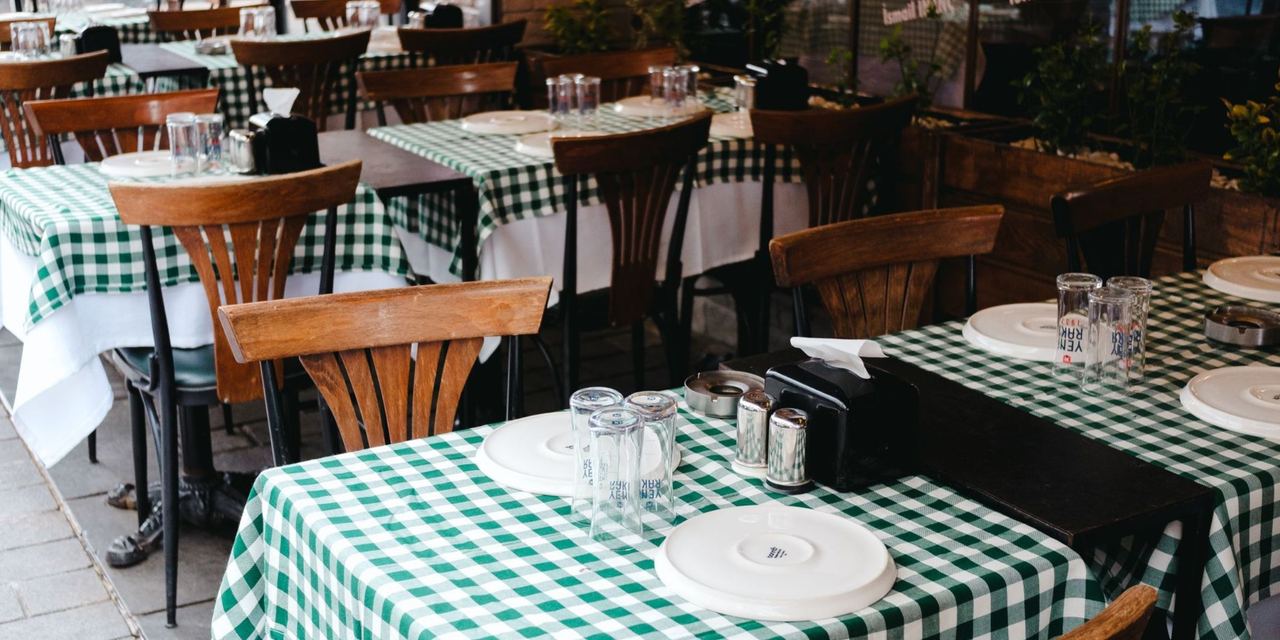 A restaurant dining area with checkered tablecloths, neatly set tables, and wooden chairs awaiting guests | Source: Pexels