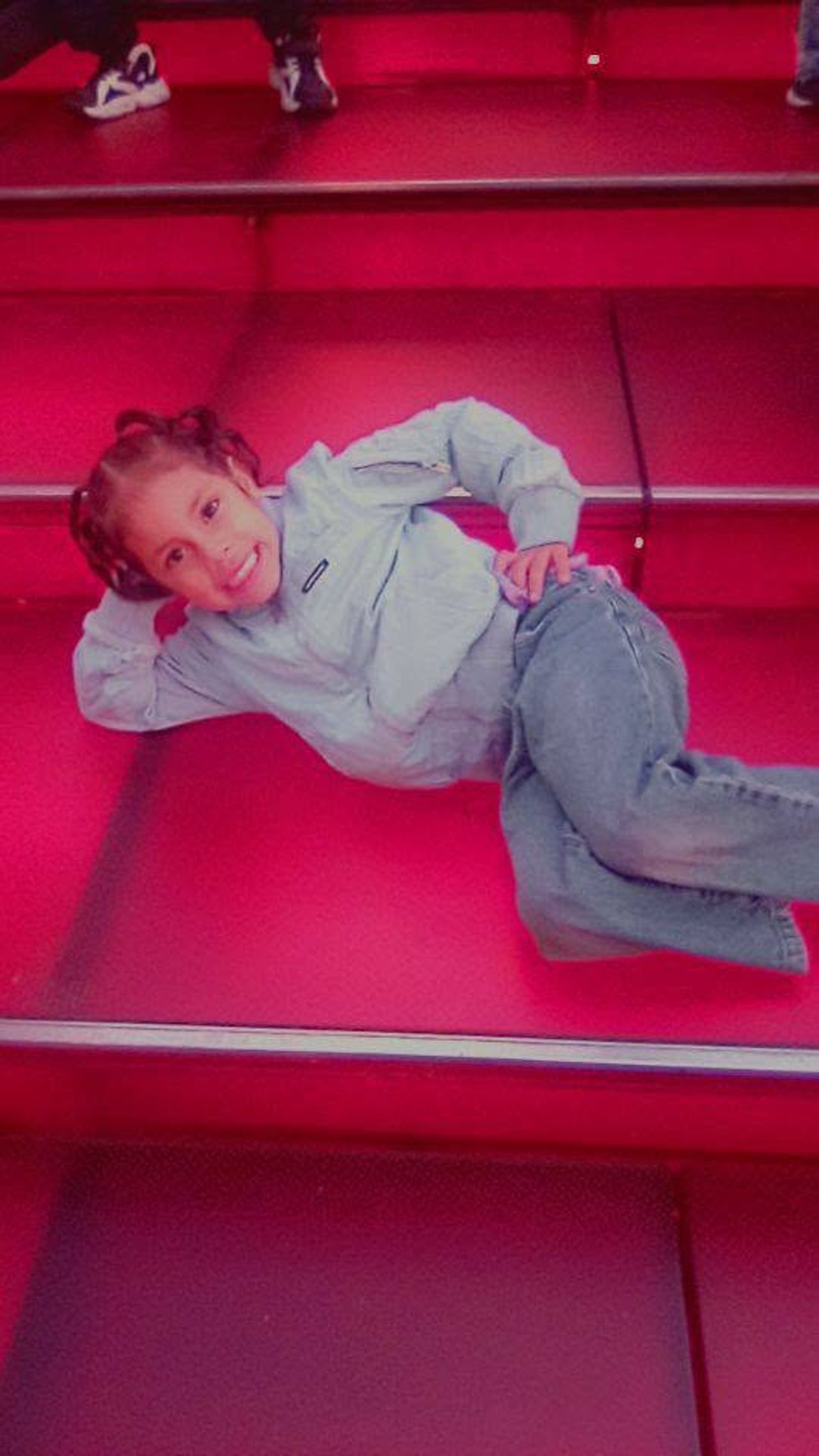 Eddimar Paola Hernández Chacón struck a fun, relaxed pose while lounging across the glowing red steps in Times Square. Leaning on one arm with a wide smile, she sported double buns, a light-blue zip-up jacket, and classic denim jeans against the bright neon red stairs. | Source: Facebook/Morena Esa