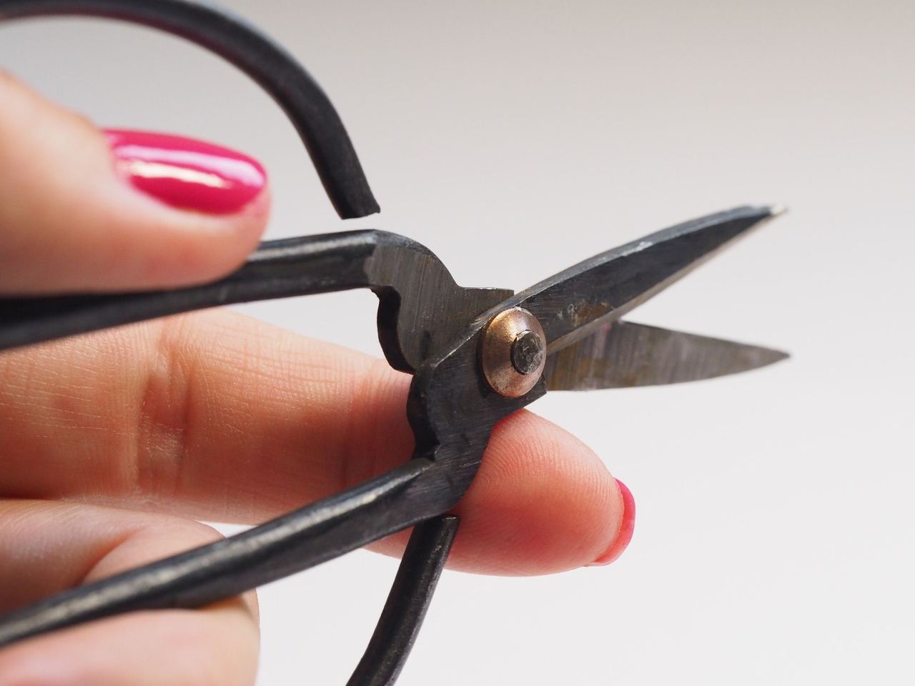 A detailed close-up of a hand with pink nail polish holding scissors, showcasing the sharp blades | Source: Pexels