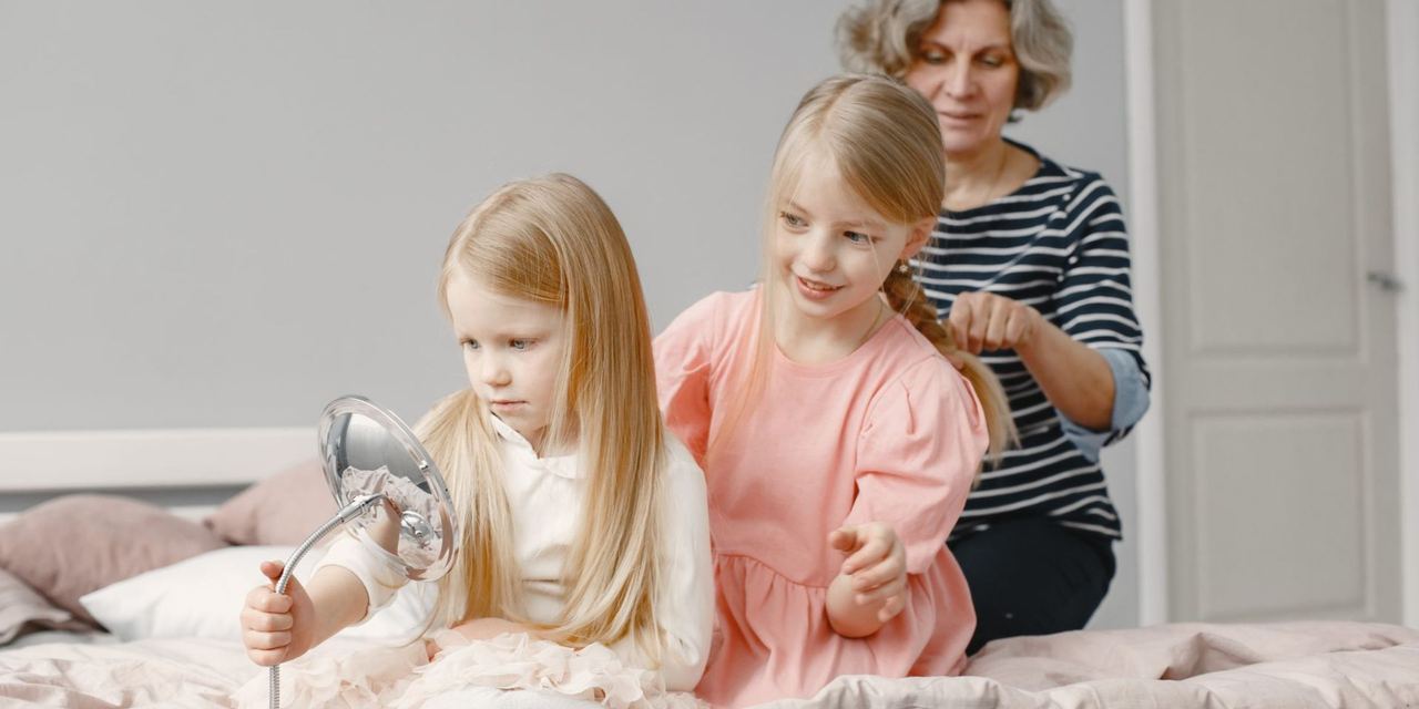 Grandmother helping her granddaughters style their hair at home | Source: Pexels