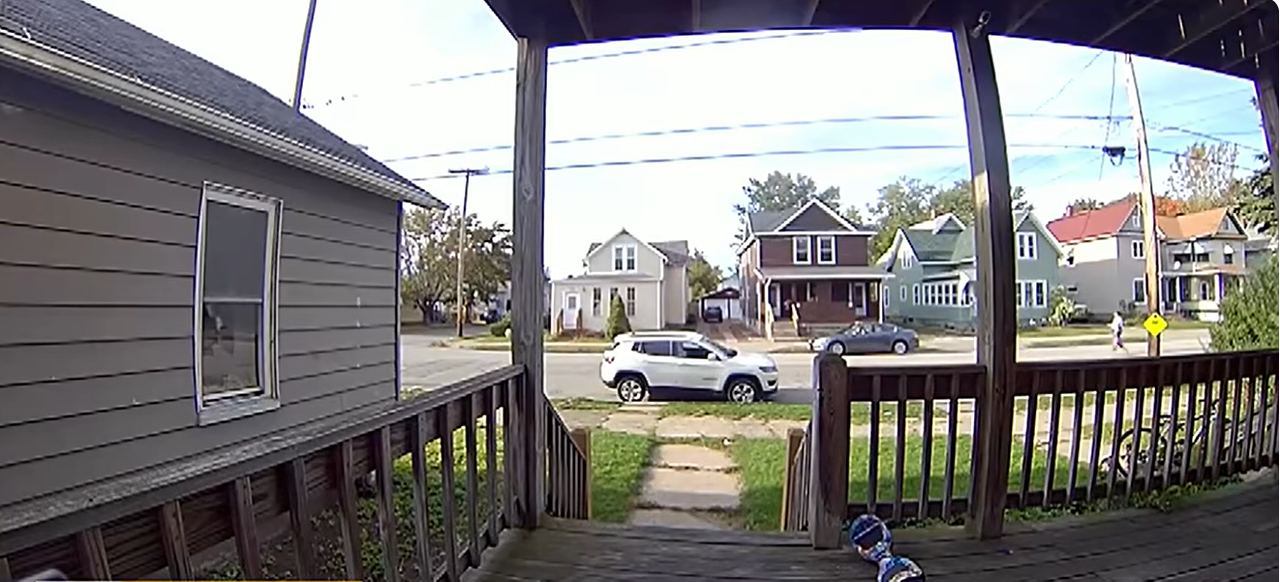 A quiet residential street in Erie, Pennsylvania, is pictured from a front porch, with parked cars and neighboring homes visible across the road. The neighborhood provides a glimpse of the setting where a deadly shooting on Perry Street left eight people dead. | Source: YouTube/ CBS Pittsburgh