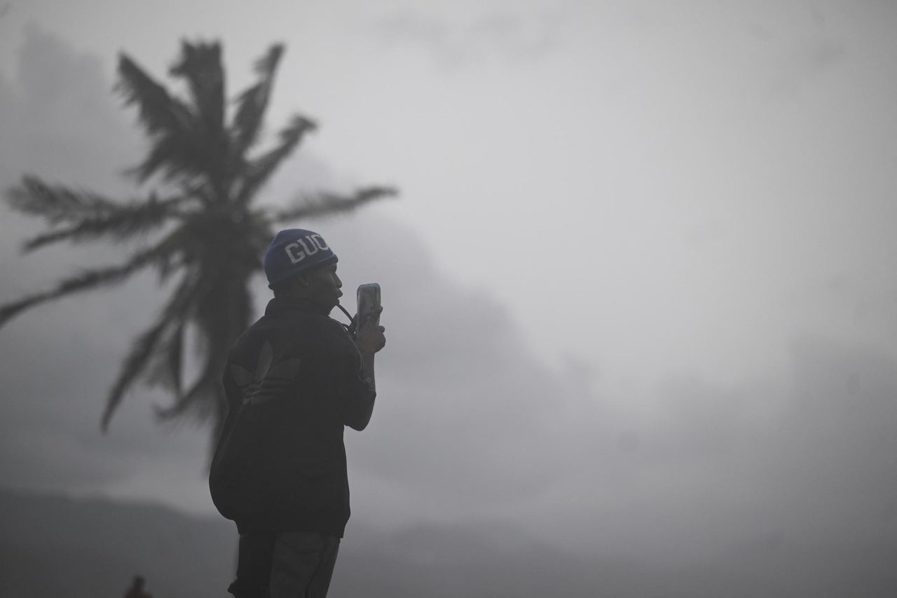 For illustration purposes: Brave onlookers and residents face the elements to document the dark, heavily overcast skies and gusty winds as a major storm moves ashore. | Source: Getty Image
