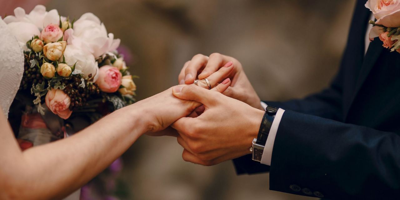 A groom placing a wedding ring on his bride's finger during their marriage ceremony | Source: Magnific