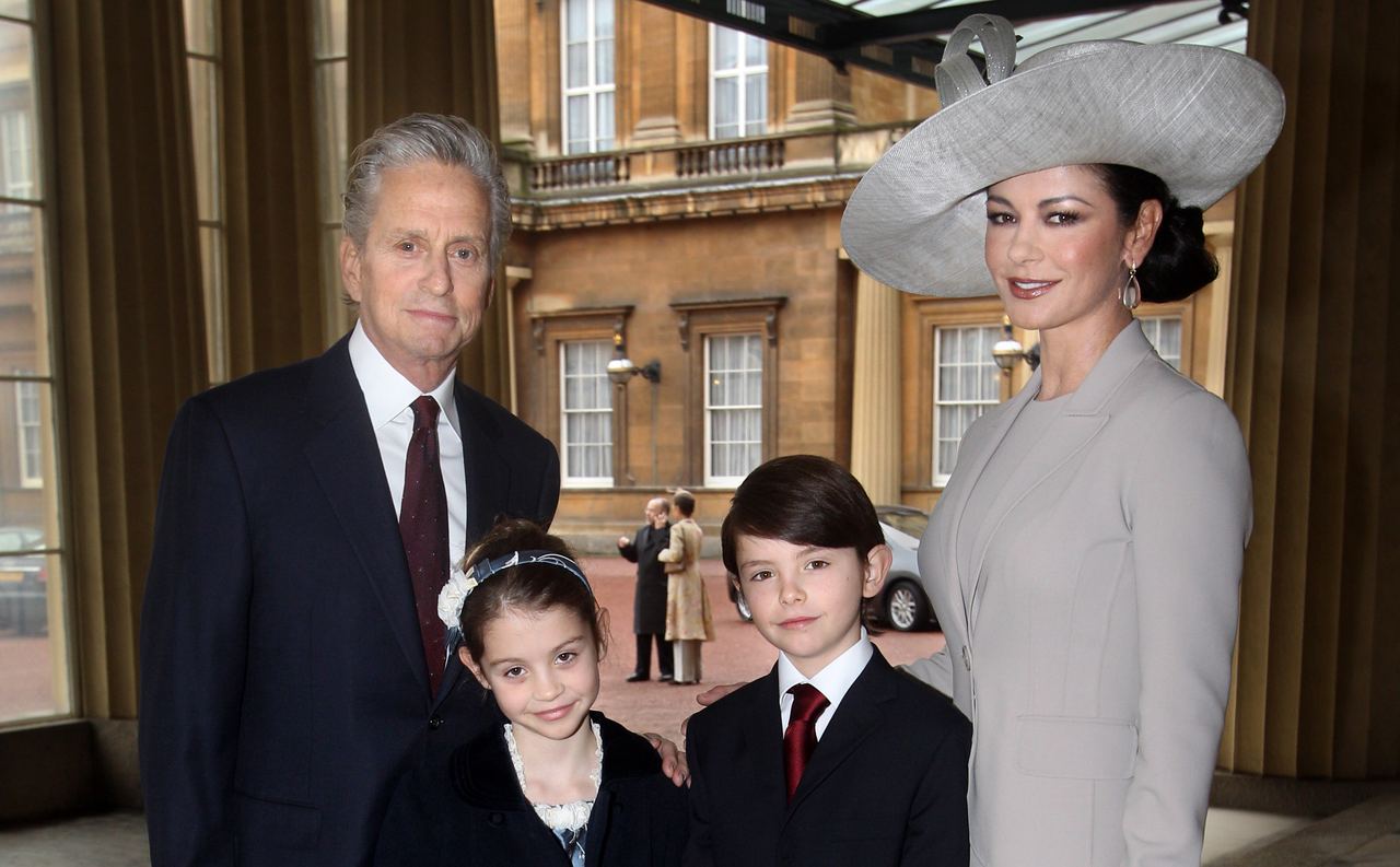 Michael and Catherine attend a royal investiture at Buckingham Palace with their children, Dylan and Carys, in 2011. The family occasion marked Catherine receiving a CBE for her contributions to film and charity. | Source: Getty Images