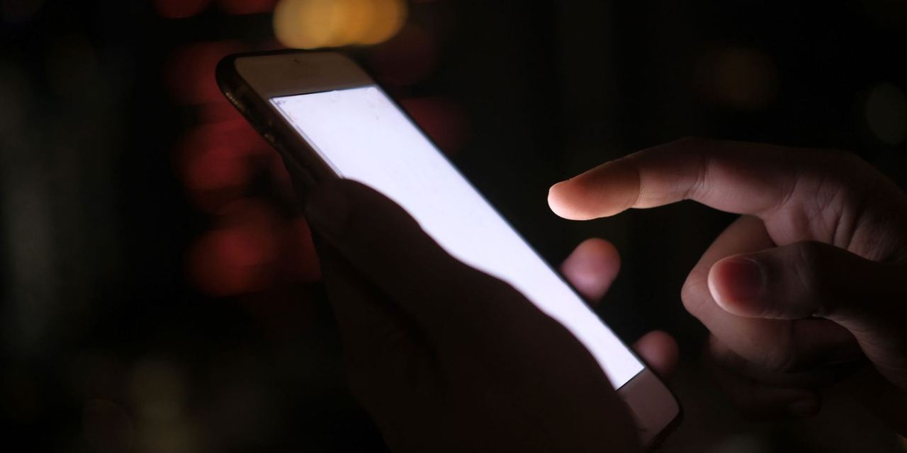 Close-up of a hand using a smartphone in the dark | Source: Pexels
