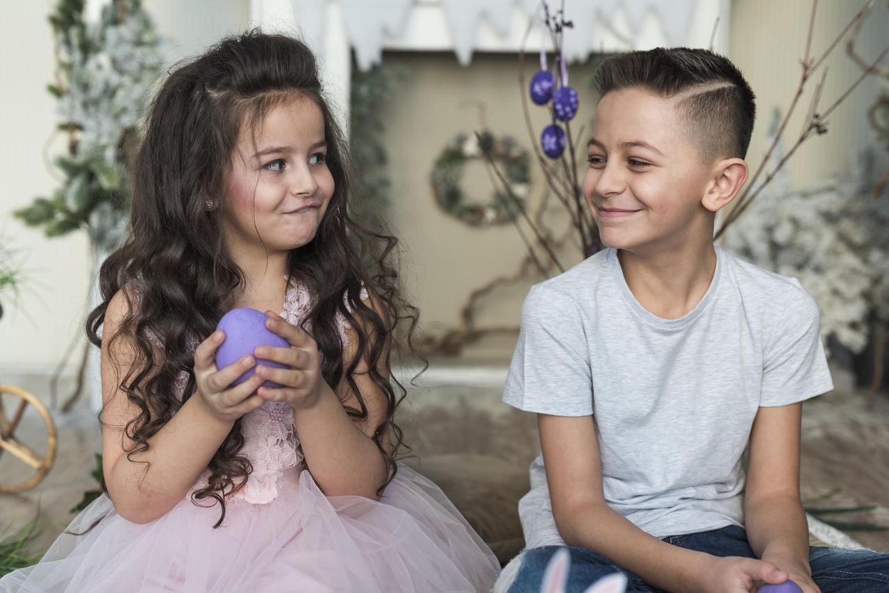 Cute boy and girl sitting with easter eggs | Source: Magnific