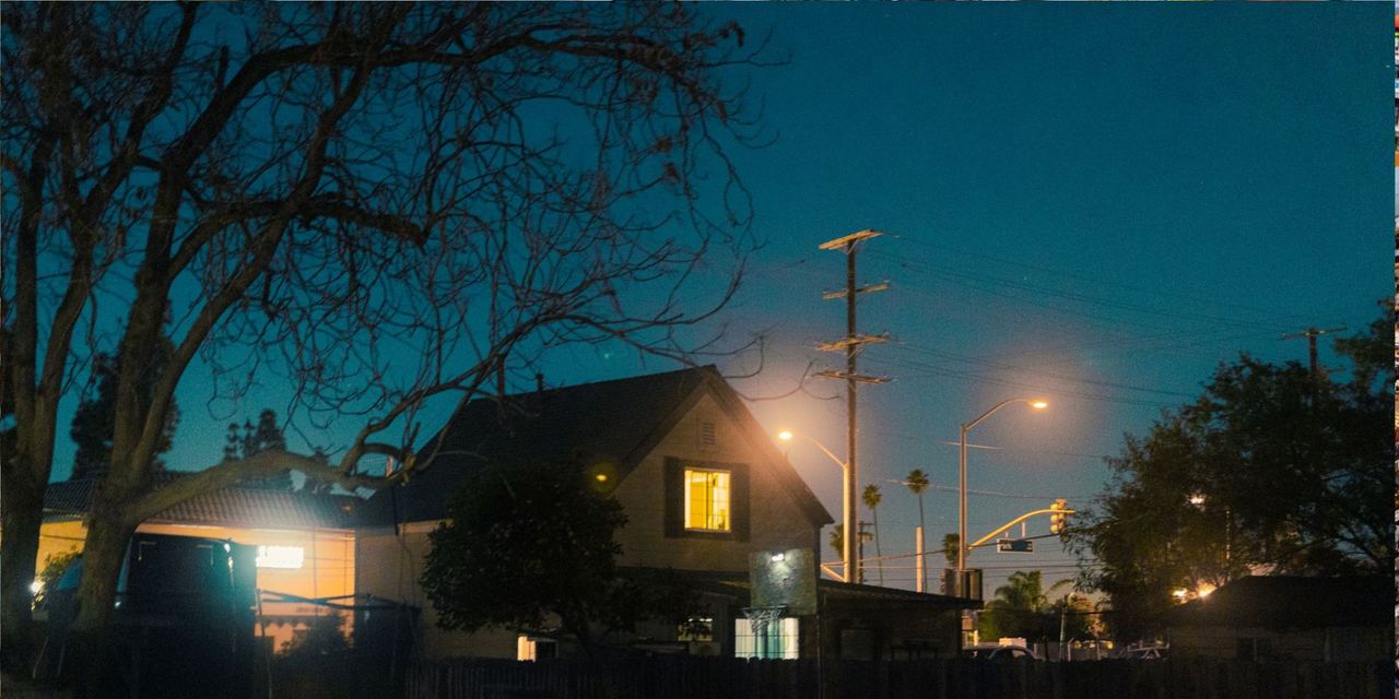 A tranquil night view of a suburb with houses illuminated by street lamps | Source: Pexels