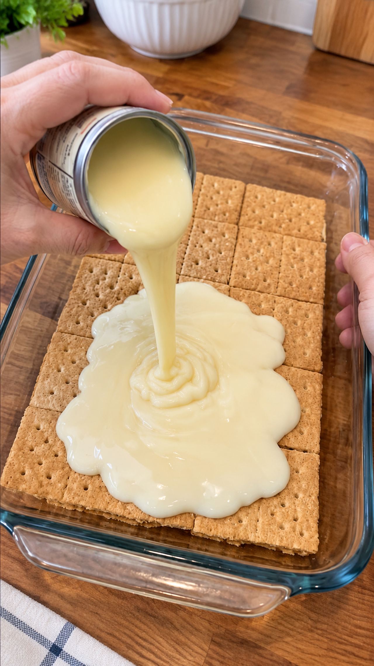 Pour sweetened condensed milk over whole, unbroken graham cracker sheets in a clear glass 