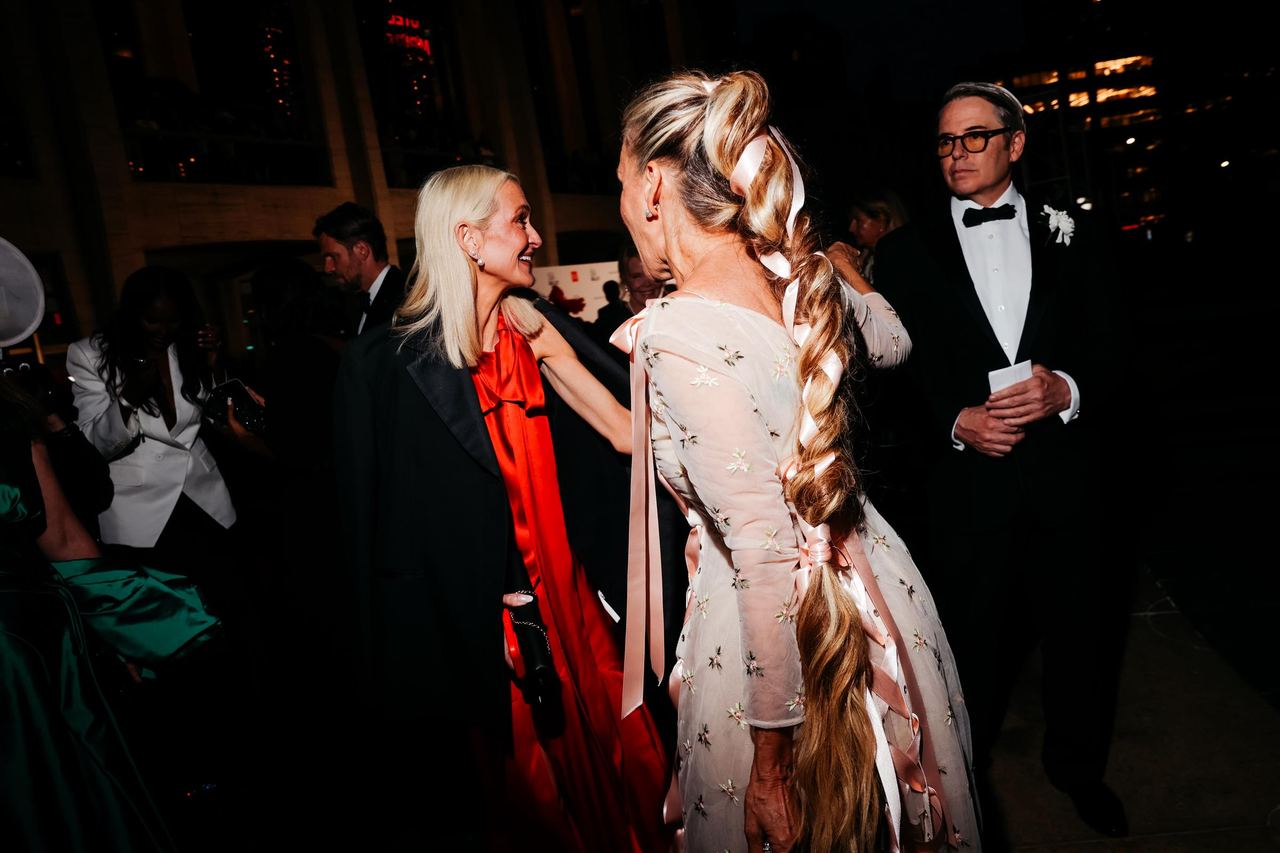 Sarah Jessica Parker's extra-long braid takes center stage, with pink ribbons woven through the hairstyle to complement her floral-embroidered gown. Matthew Broderick stands nearby in a classic black tuxedo. | Source: Getty Images