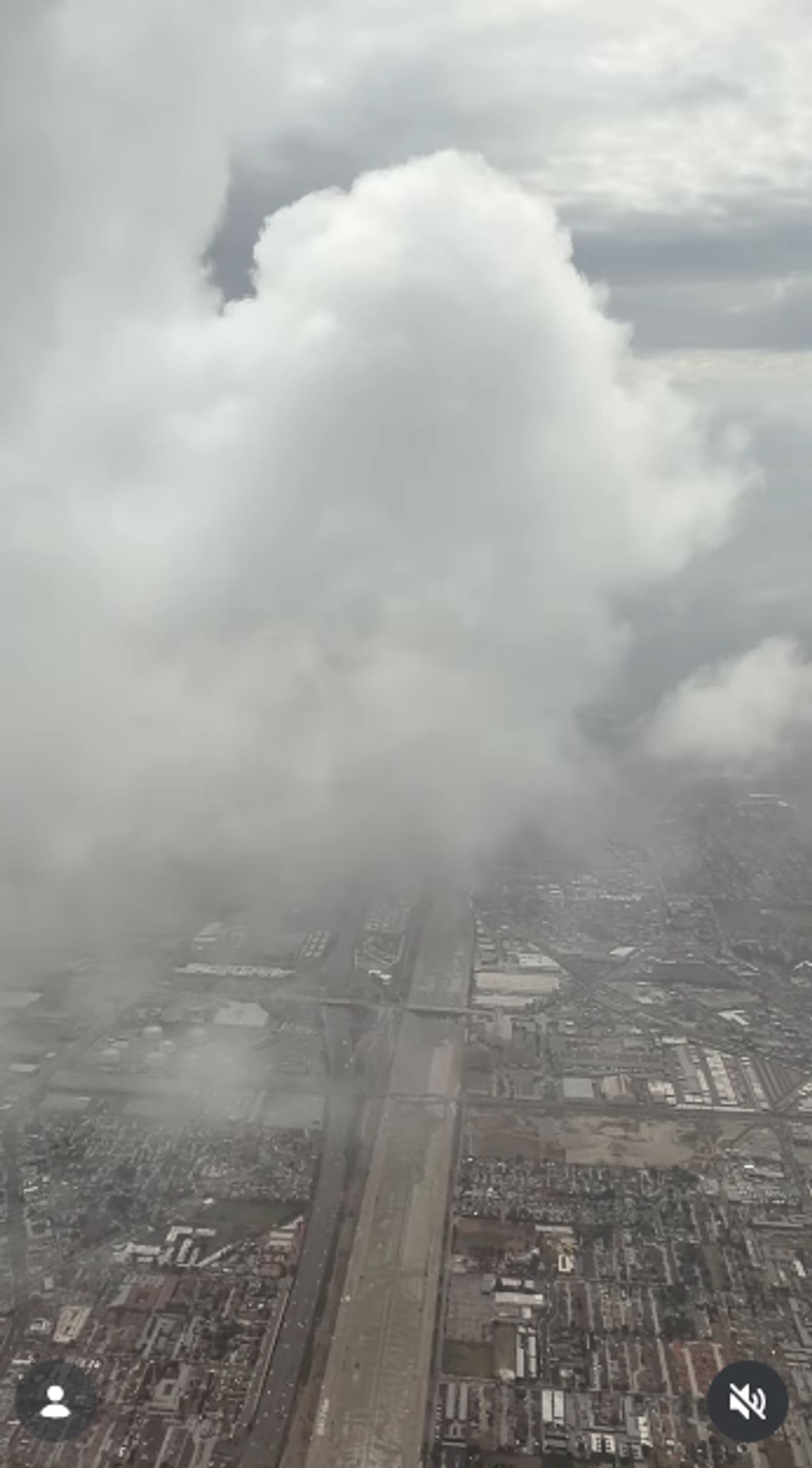 An airplane window perspective frames heavy overcast storm clouds hanging over expansive city grids and highways on October 11, 2026. Towering cumulus masses fill the sky, partially obscuring the urban layout below during transit. | Source: Instagram/selmablair