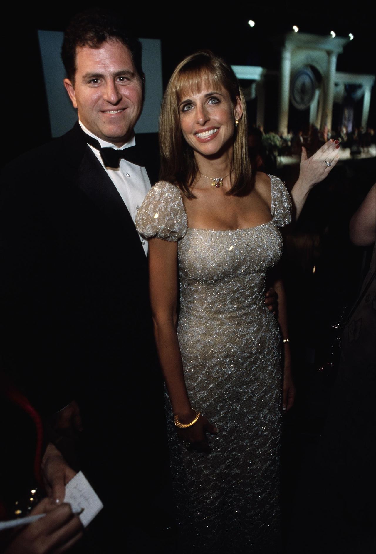 Dell founder Michael Dell and his wife, Susan, smile together while attending President George W. Bush's Inaugural Ball on January 20, 2001. Michael wears a classic black tuxedo with a crisp white shirt and black bow tie, while Susan stands beside him in an intricately beaded, cap-sleeved gown accessorized with a necklace, gold bracelet, and rings. | Source: Getty Images