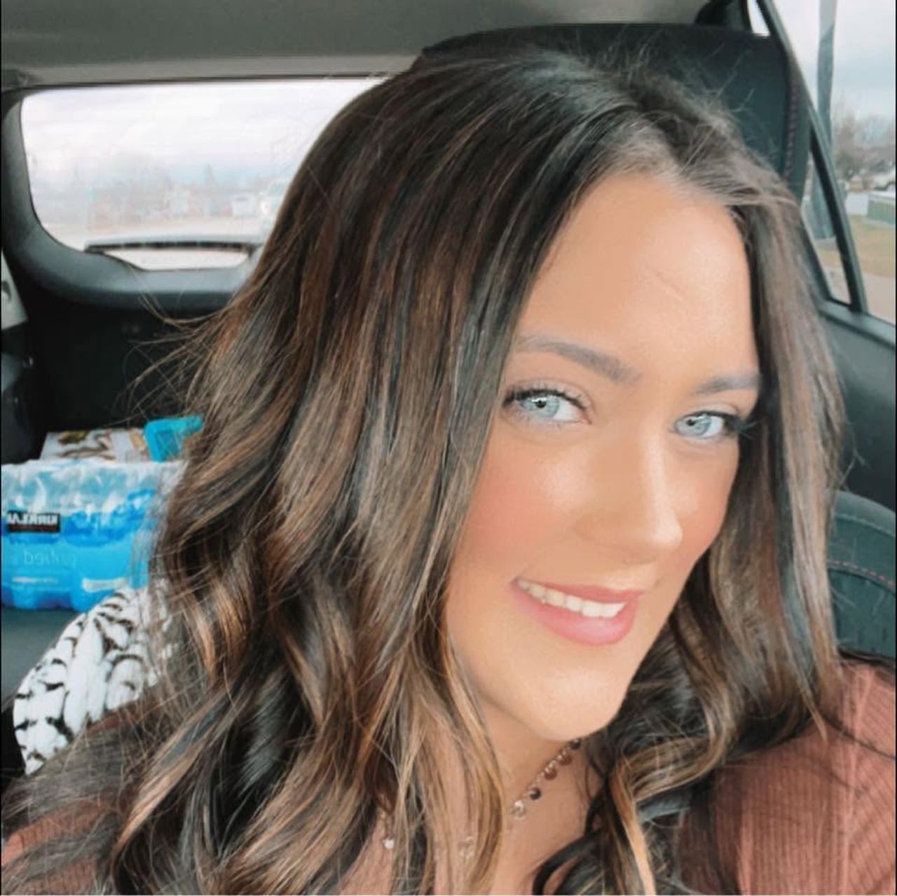 Hannah Jorgensen smiles warmly in a close-up selfie taken from inside a vehicle, showing her styled wavy brunette hair with highlights. | Source: Facebook/Hannah Jorgensen